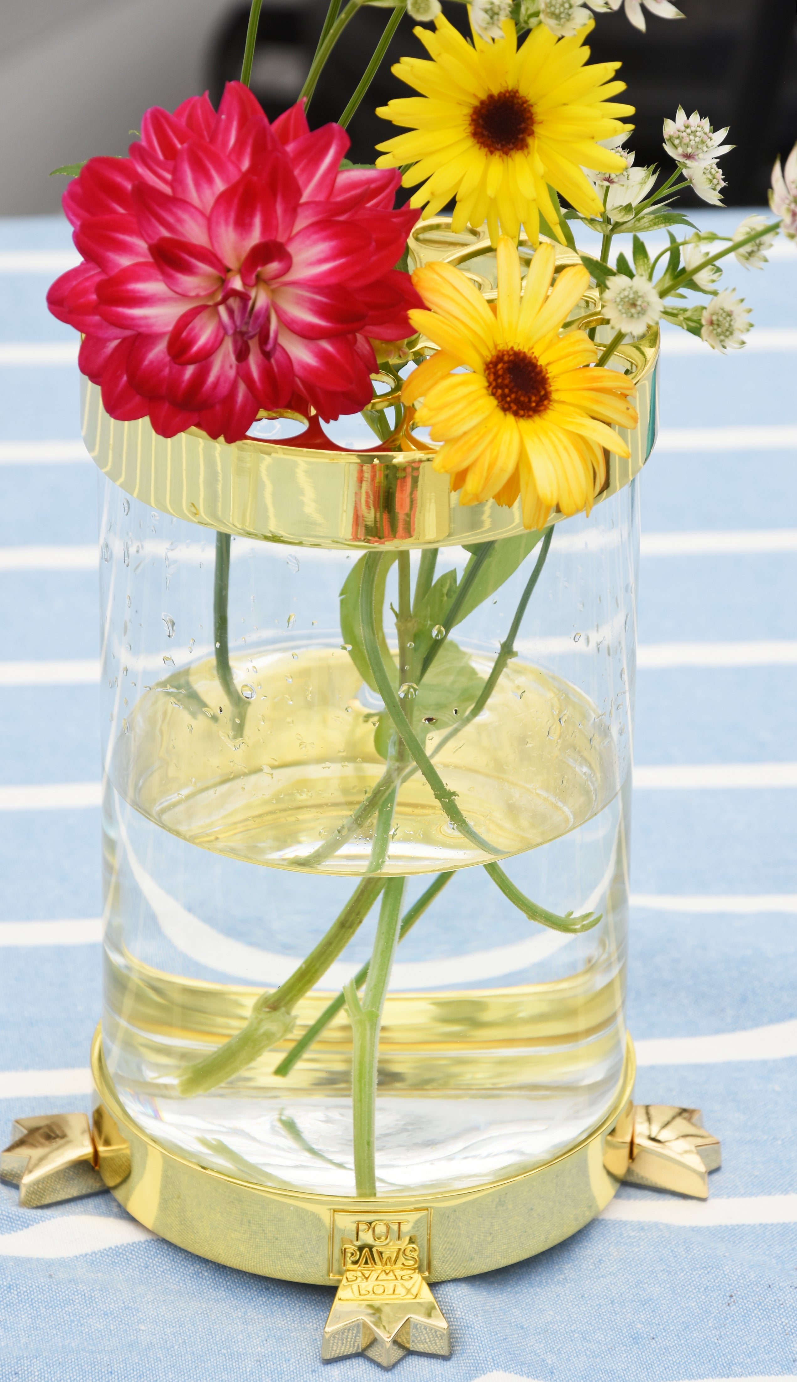 Clear glass vase with gold rim and base holding colorful flowers on table