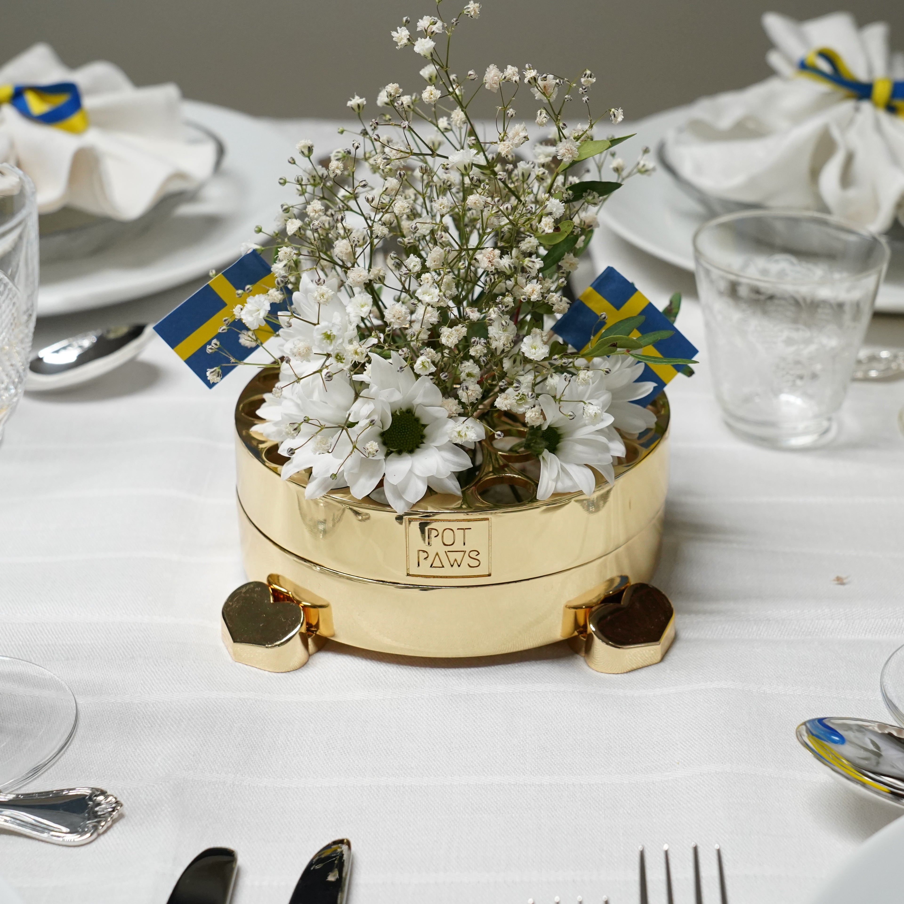 Gold POT PAWS floral table centerpiece with white flowers and heart-shaped feet on a set dining table