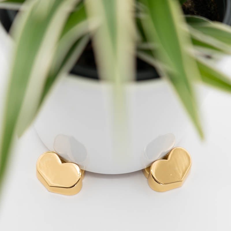 White plant pot raised on gold heart-shaped POT PAWS pot feet for drainage and surface protection