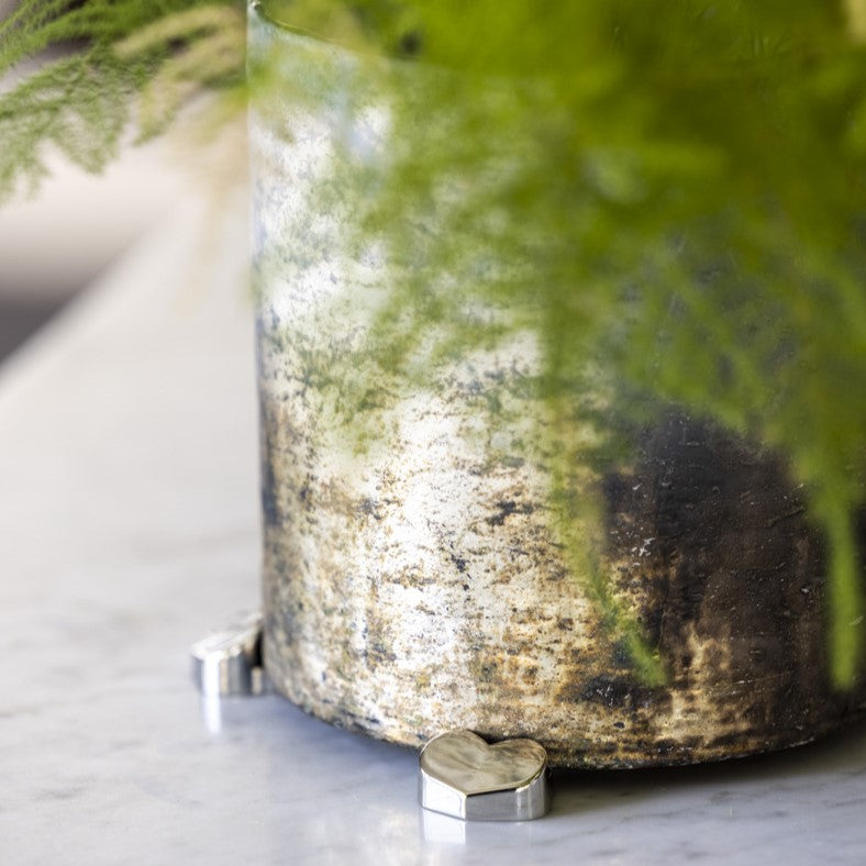 Silver heart-shaped POT PAWS feet lifting a glass planter to protect surfaces